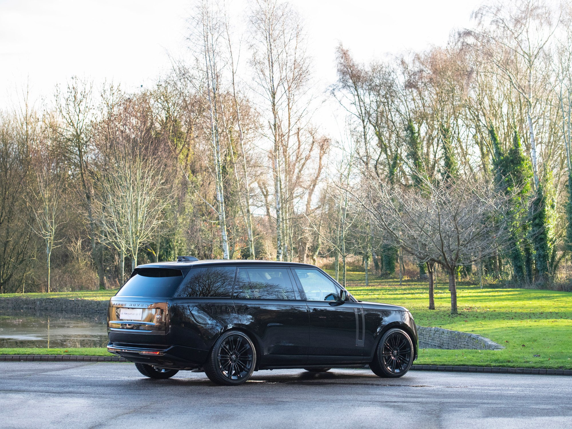 Range Rover Autobiography LWB in black, rear three-quarter view in a parkland setting